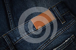 Blank brown leather label sewed on a blue denim jeans. Mock up jeans tag