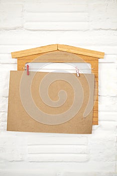 Blank brown paper hanging with house wooden decorate on white wa