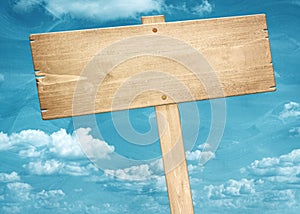 Blank brown wooden signpost against blue sky.