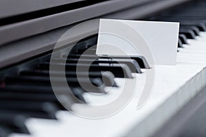 Blank business card placed between piano keyboard racings