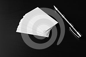 Blank business cards with pen on dark background