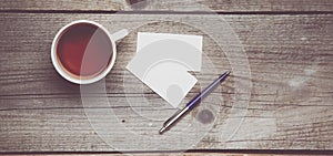 Blank business cards with pen and tea cup on wooden office table