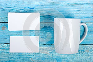 Blank business cards, white cup on the wooden table. Template for ID. Top view. A cup of coffee.