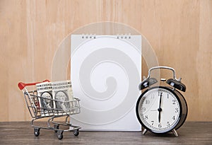 Blank calendar planner with clock and cart shopping on wood desk