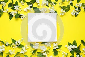 Blank canvas and beautiful jasmine flowers on yellow background, flat lay. Space for design