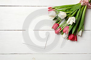 Blank card for invitation or congratulation with bunch of white tulips flowers on white wooden table. Vintage banner mockup for sp