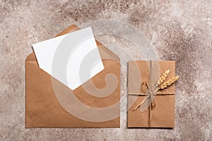 Blank card mockup in a craft envelope. Vintage letter tied with twine with ears of ripe wheat. Invitation template. Beige grunge