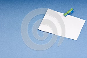Blank card with space for notes on the wooden clothespin colored paper on blue background