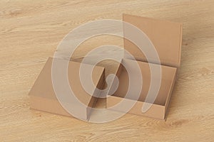 Blank cardboard flat square gift box with open and closed hinged flap lid on wooden background.