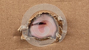Blank cardboard form, craft paper, hole with Human eye, Young child 10-12 years old looking straight, covertly is following,