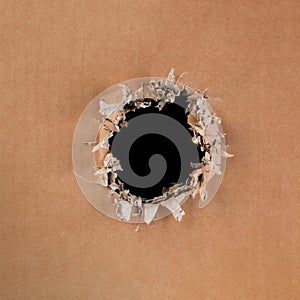 Blank cardboard with rough, ripped and torn hole in the center with blank black space