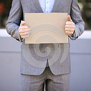 Blank, cardboard and unemployment person with suit, poster and mockup for job hunting outdoor. Professional, hands and