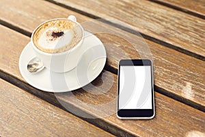Blank cell phone and cup of coffee on a wooden table
