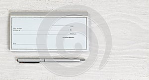 Blank checkbook and silver pen on white desktop photo