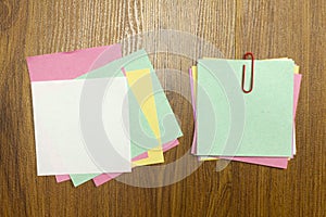 Blank colorful note paper with red paper clip on wooden desk
