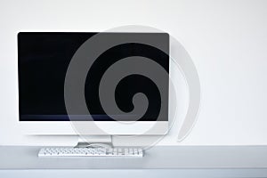 Blank computer screen with mouse and keyboard on the office desk, white background