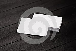 Blank corporate identity business card and stack on black stylish wood background with blur, template.