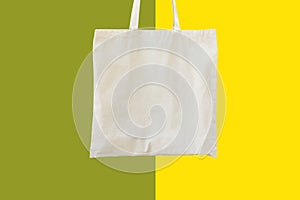 Blank cotton shite shopper tote bag on duotone green yellow background. Mock up template for product branding plastic free