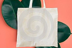 Blank cotton shite shopper tote bag on pink background with green leaves. Mock up template for product branding plastic free photo