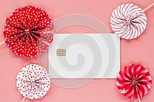 Blank credit chip card with red and white paper fan on pink back