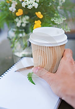 Blank cup of coffee in woman hand and sheet of paper. Mock up design