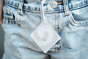 blank diamondshaped tag hanging from the pocket of a childs denim shorts