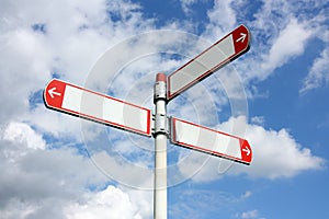 Blank directional road signs against a blue sky with clouds