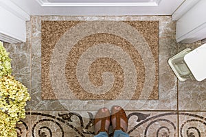 Blank doormat before the door in the hall. Mat on ceramic floor, flowers and shoes. Welcome home, product Mockup