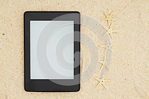 An e-reader on the beach for your summer reading with five starfish