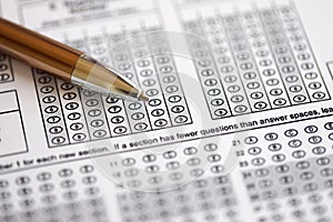 Blank educational test for students lies on table in classroom with pen