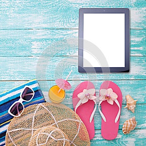 Blank empty tablet computer on beach. Trendy summer accessories on wooden background pool. Sunglasses, orange juice and