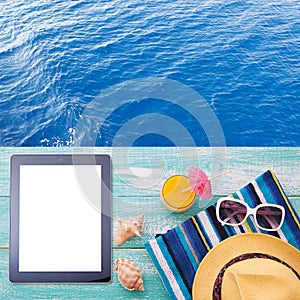 Blank empty tablet computer on beach. Trendy summer accessories on wooden background pool. Sunglasses, orange juice and