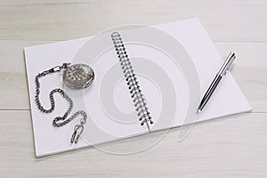 Blank empty white page note book opening with pen and vintage pocket watch on gray wooden table using as time, journal thinking,