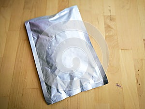 Blank Foil plastic pouch bag on wooden background.