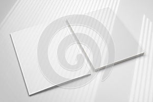 Blank folder and letterheads stack on white desk with shadow overlay as template for design, logo presentation, branding mock-up