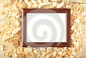 Blank frame on wooden background with sawdust.