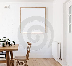Blank framed print on white wall in danish styled interior dining room