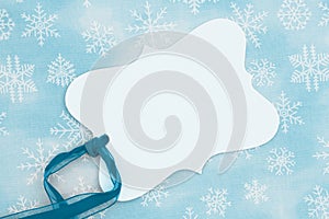 Blank gift tag with a blue ribbon on snowflakes