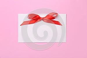 Blank gift tag with satin ribbon on color background