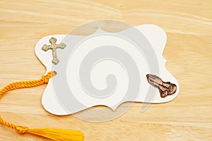 Blank gift tag with yellow ribbon praying hands and cross on wood desk