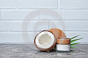 Blank glass white mockup jar of cosmetic facial cream with golden lid and fresh coconut with green palm leaf