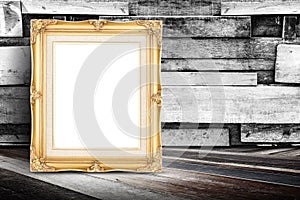 Blank golden vintage photo frame leaning at plank wood wall and