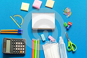 Blank graphing paper notebook with school supplies frame against a bright blue wall. Copy space.banner.advertisement