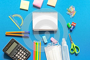 Blank graphing paper notebook with school supplies frame against a bright blue wall. Copy space.banner.advertisement