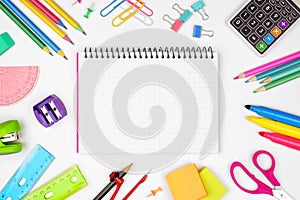 Blank graphing paper notebook with school supplies frame against white with copy space. Back to school.