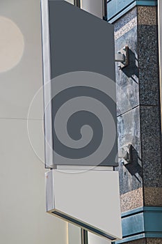 Blank gray vertical sign affixed to the side of a building.