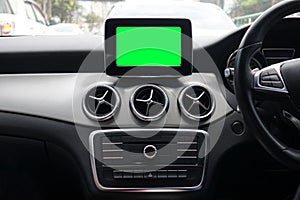 Blank green screen of monitor inside a modern car interior using for navigation maps and GPS in transportation and travel concept