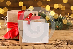Blank greeting card and Christmas gift on wooden table. Space for text