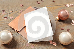 Blank greeting card, envelope and Christmas balls on wooden table. Space for text