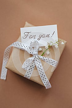 Blank greeting card and gift box on beige background.